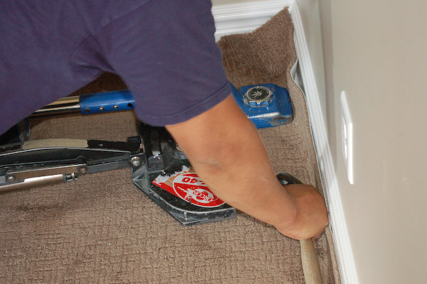 pressing carpet into tack strip with carpet stretcher